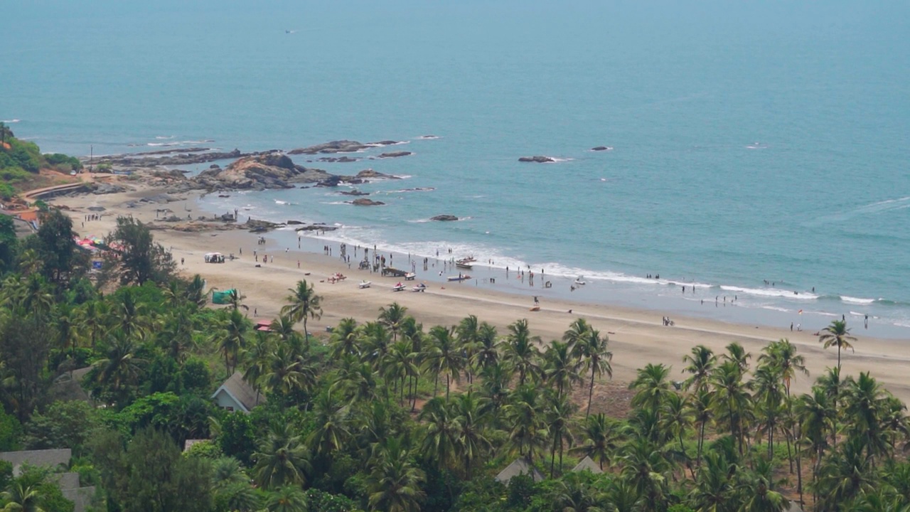 航拍的Vagator海滩，人们在印度果阿的海滩上度过他们的时光。夏天，海边的游客在海滩上享受自己。蓝色海滩的游客。视频素材