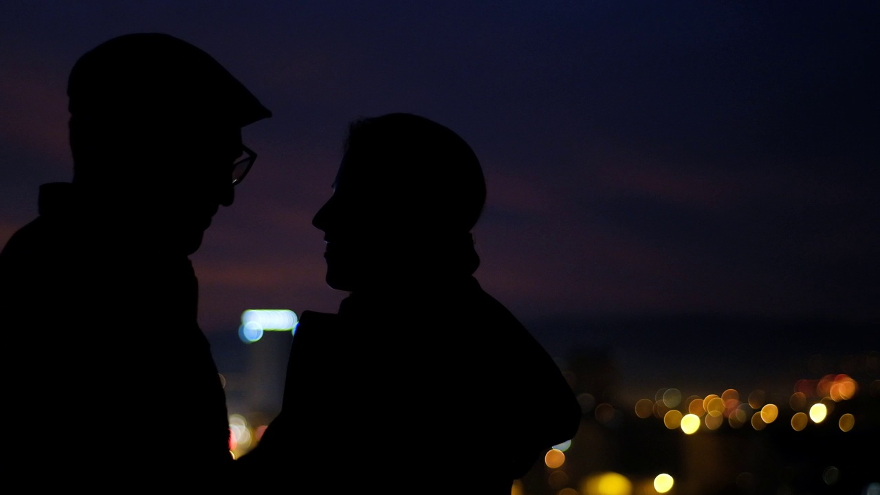 一对情侣在城市的夜晚亲吻的剪影视频素材
