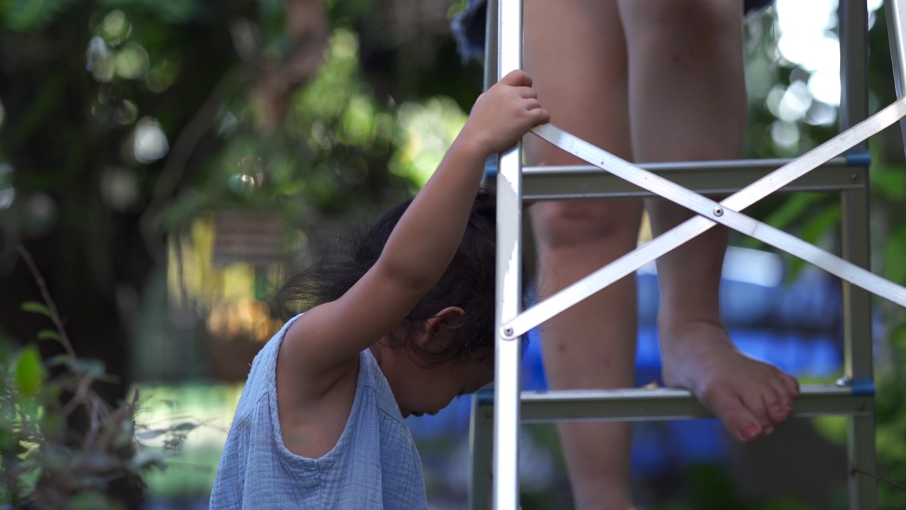 一个小孩玩金属梯子的特写，有人站在上面视频下载