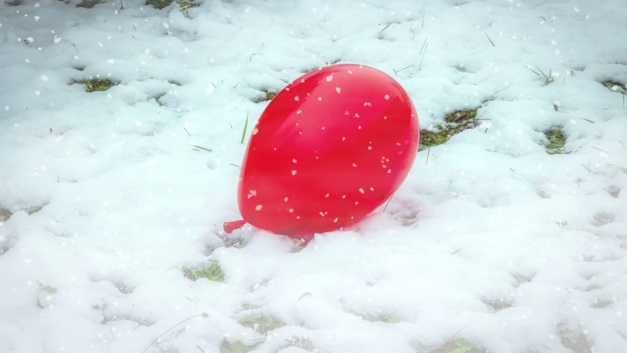 红色的气球躺在雪花纷飞的雪地上视频下载