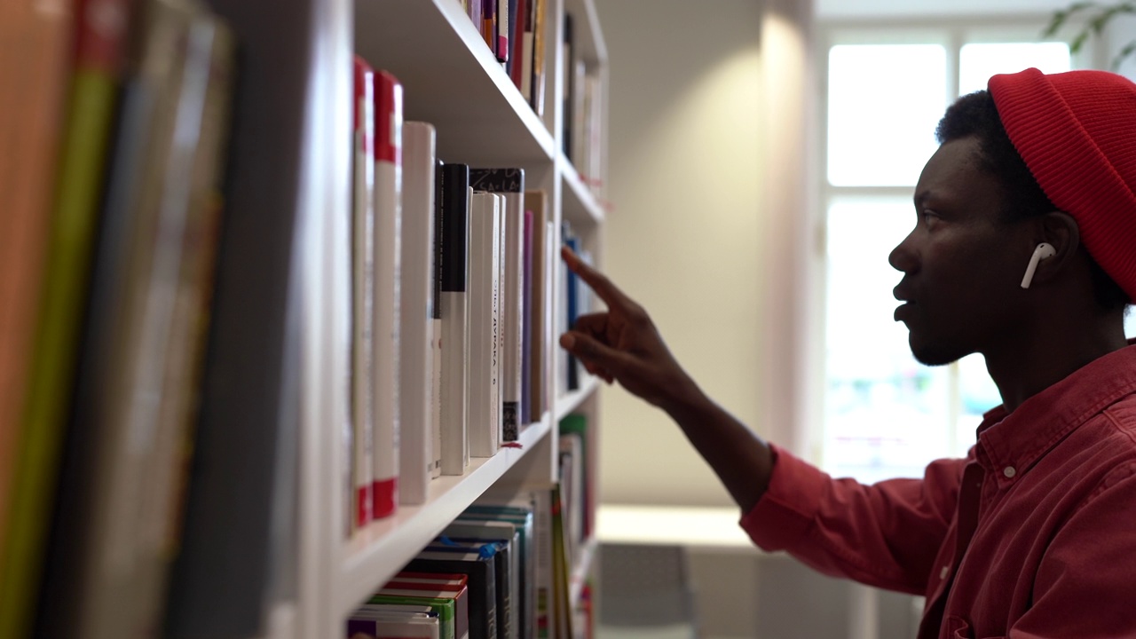 年轻的非洲千禧男学生从大学图书馆的书架上拿起正确的书视频素材