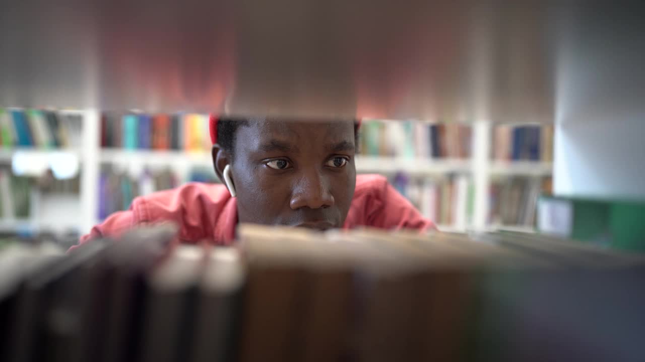 疲惫焦虑的黑人学生站在书架之间，在大学图书馆找不到书视频素材