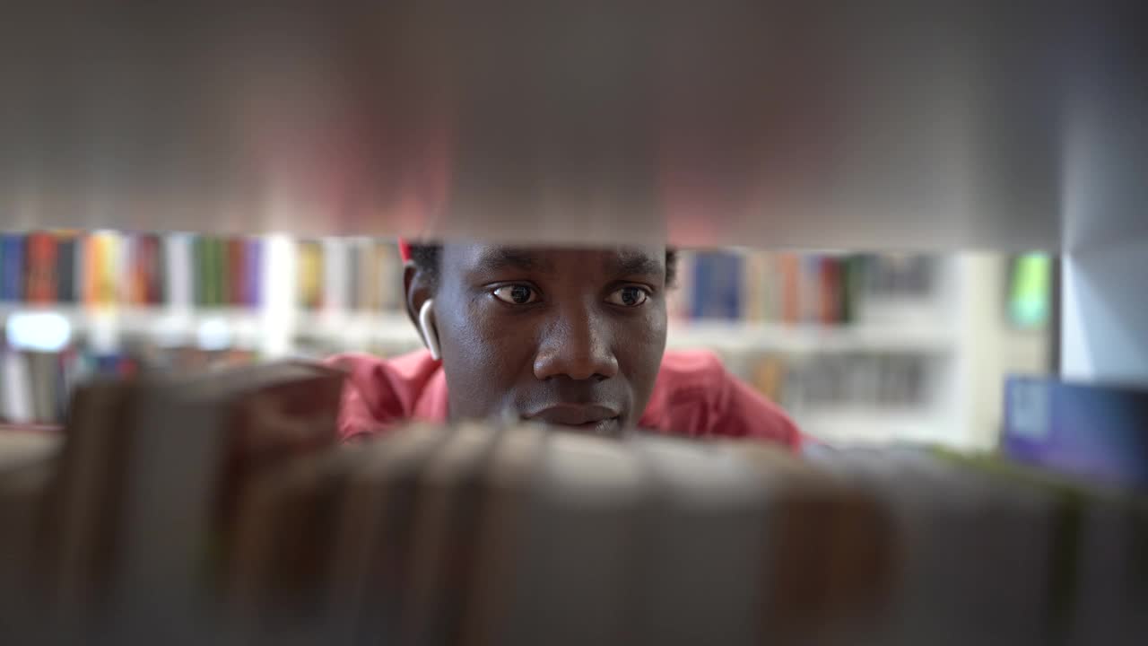 非裔美国男子图书管理员在图书馆工作，从书架上取书视频素材