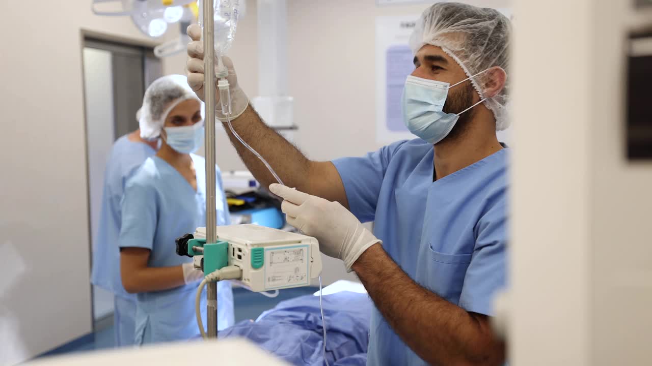 手术室的护士团队在手术前给病人进行生理盐水和药物的准备视频素材