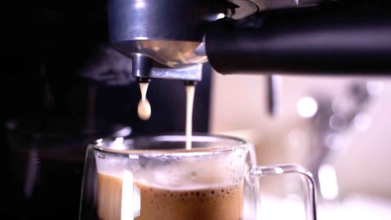 咖啡泡沫特写。浓缩咖啡从全自动咖啡机里出来，把咖啡机变成杯子。软的焦点。视频素材