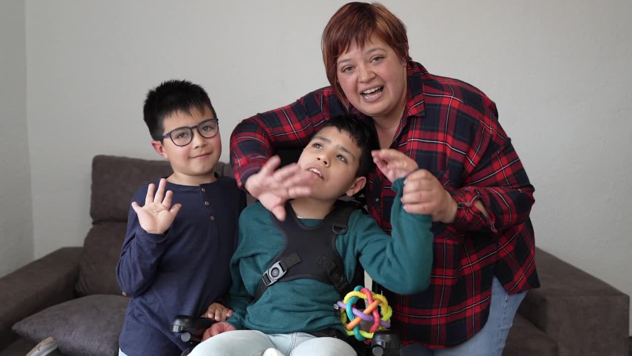 残疾儿童坐在轮椅上的家庭对着镜头挥手视频下载