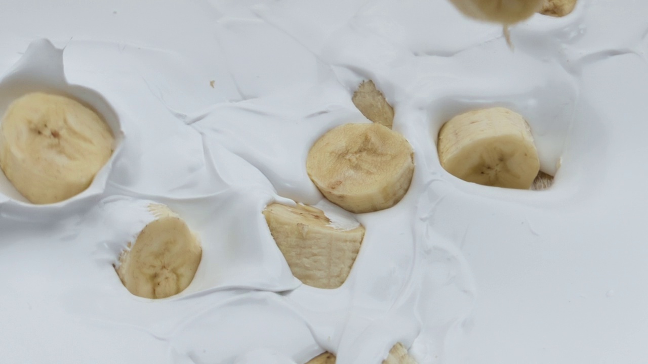 在超慢动作特写中，甜美的香蕉酸奶溅落。视频素材
