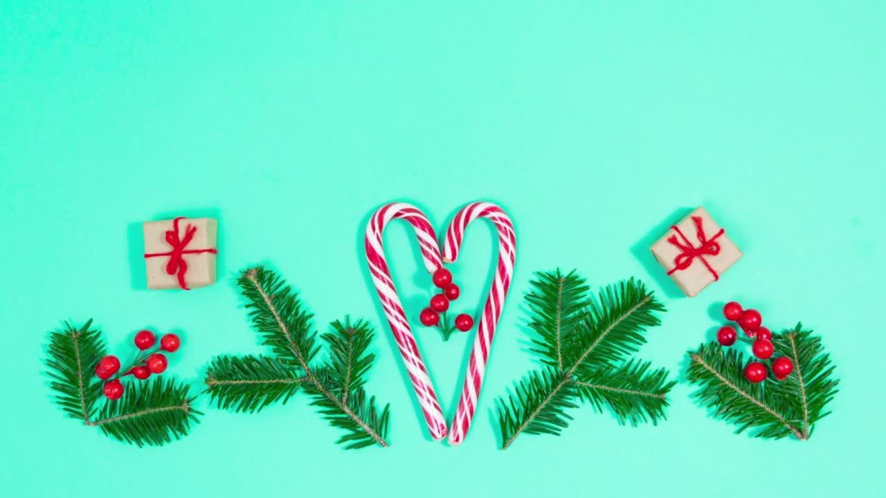 4k礼品盒围绕着云杉树枝、装饰性的红色浆果和心形拐杖糖旋转。漂亮的圣诞贺卡。圣诞快乐。视频下载
