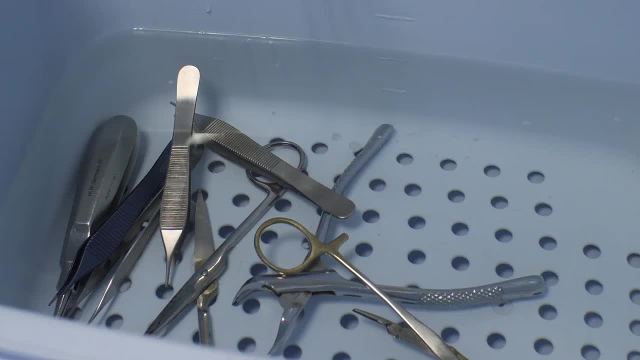 助手洗完手术器械后，把它放在一盆水里。仪器在蓝色的盆里用溶液消毒。清洁手术器械的概念。视频素材