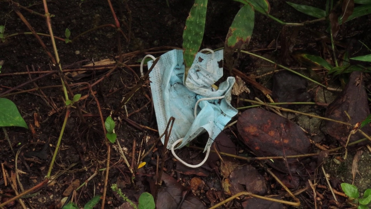一个又旧又脏的蓝色医用口罩上的垃圾躺着视频素材