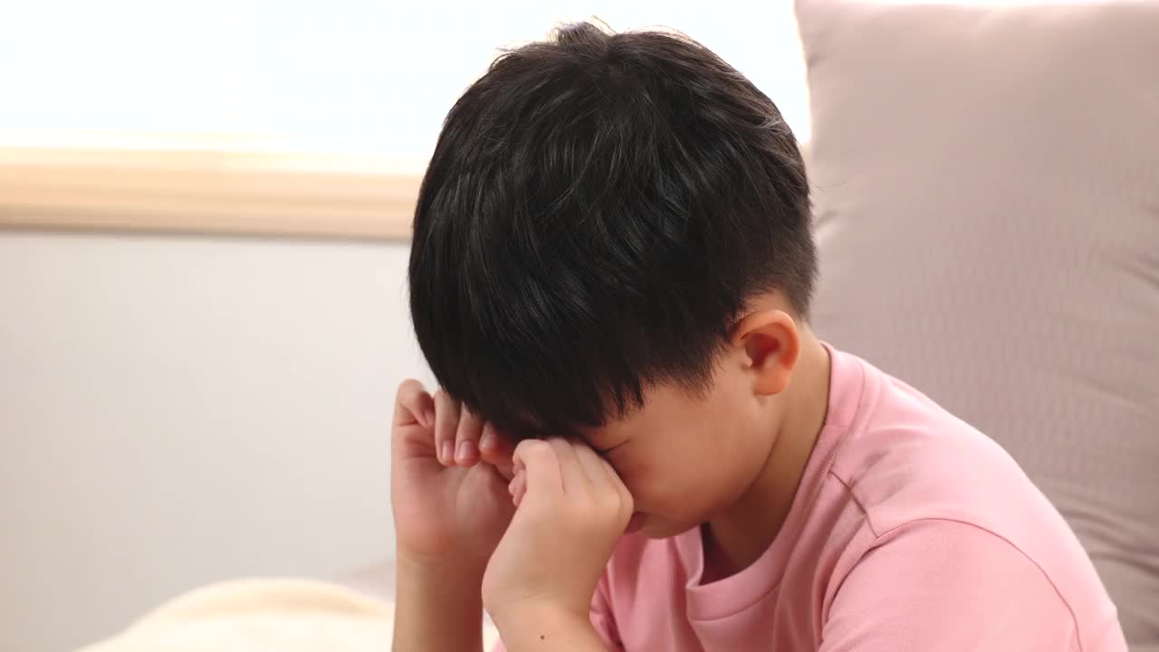 亚洲可爱的男孩哭着没有眼泪心烦意乱想玩游戏却不被妈妈允许，孤独的孩子陷入麻烦家庭破裂的问题，小学多动症可爱的男孩沮丧担心上学视频素材