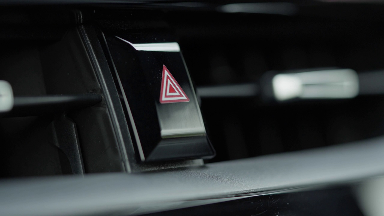 食指按在汽车仪表板上的乘用车危险灯按钮的特写。事故紧急标志和情况视频素材