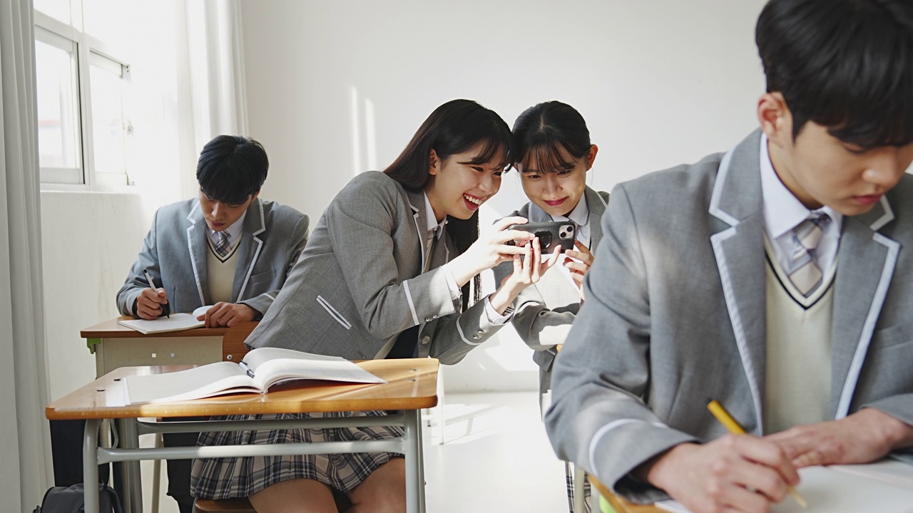 在高中课间休息时，女生们拿着手机相视而笑视频素材