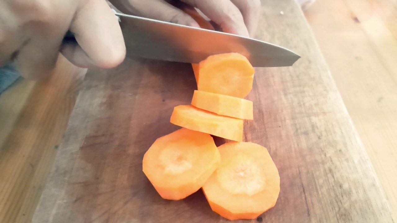 女人用刀在木砧板上切胡萝卜视频素材