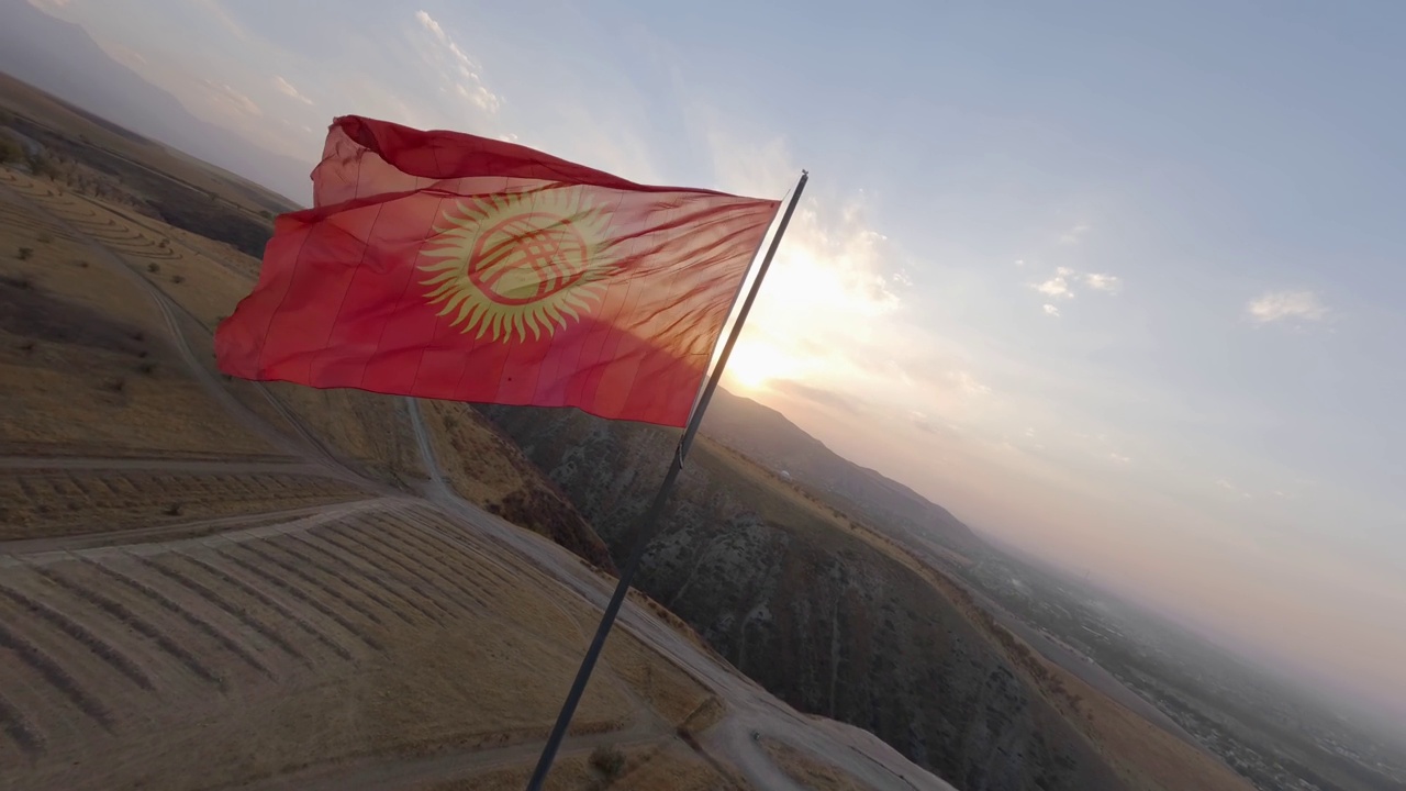 吉尔吉斯斯坦波纹旗杆视点在山场山谷日落景观空中全景视图视频下载