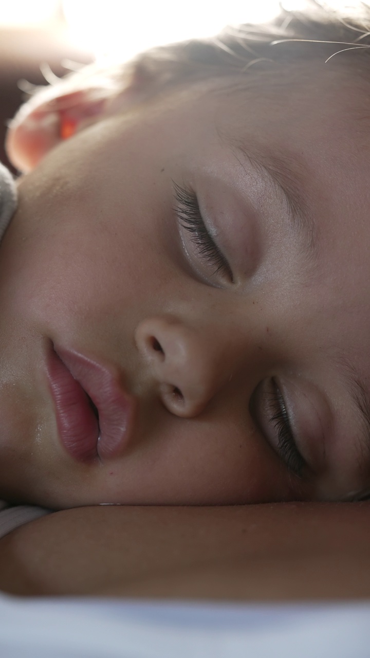 一个小男孩睡着了。孩子近距离看脸打盹。孩子在垂直视频里睡觉视频素材