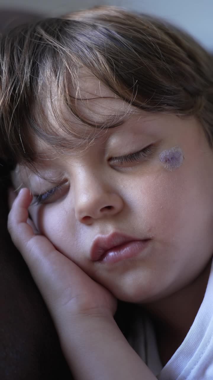 一个小男孩在沙发上午睡。特写孩子的脸睡觉。孩子在家里打盹在垂直视频视频素材