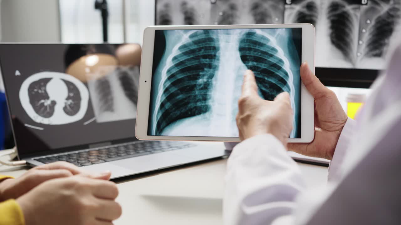 新冠肺炎康复后，高级女医生向患者解释平板电脑上的肺部扫描视频素材
