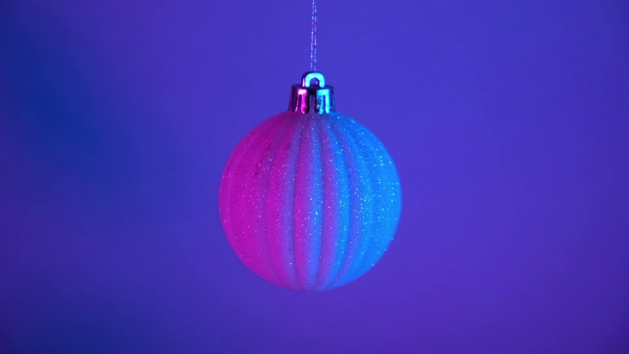 霓虹灯下的圣诞舞会。2023年新年。球挂在蓝粉红色的背景。圣诞快乐视频下载