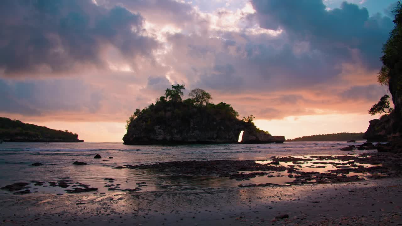 日落时分，印度尼西亚巴厘岛水晶湾海滩上黑暗多云的彩色天空。悬崖轮廓暮色浅平静的海水。视频素材