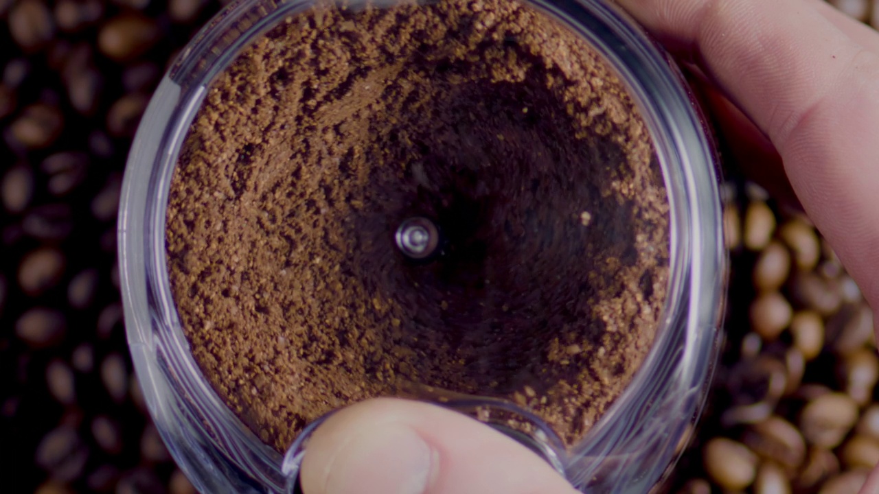 俯视图电动研磨机准备咖啡粉特写。研磨种子旋转视频下载