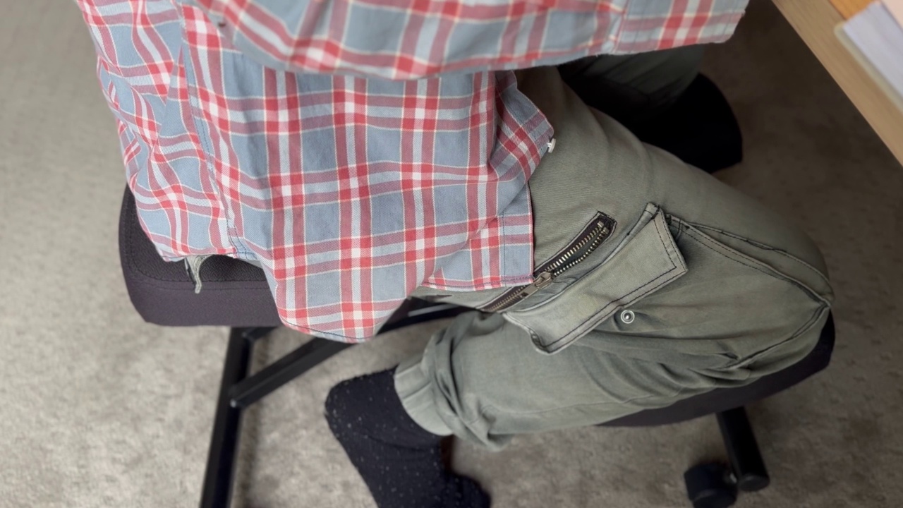 一名男子坐在一张符合人体工程学的跪椅上。视频下载