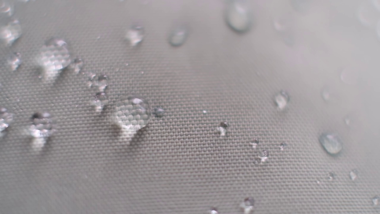水溅在防水织物上的慢动作镜头。织物上的水珠。防水涂料背景有水滴。柔焦，模糊视频素材
