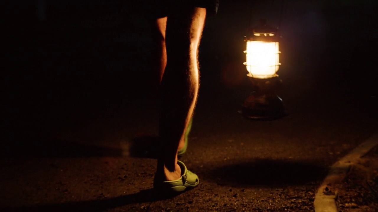 一个男人拿着汽油灯走在夜路上。视频下载