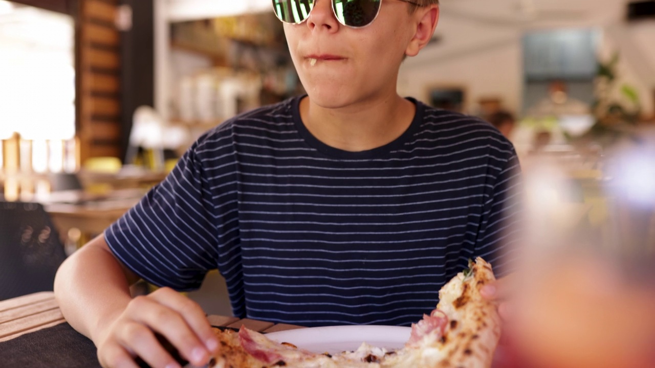 十几岁的男孩非常喜欢吃披萨。视频素材