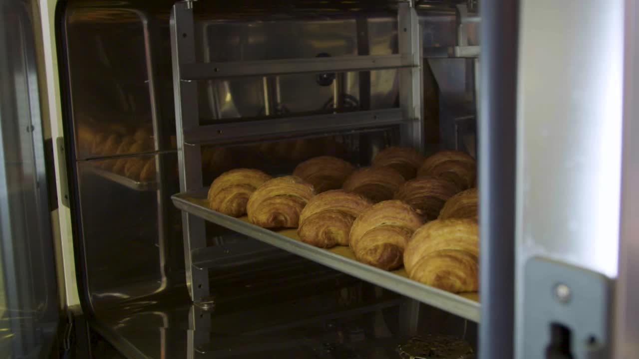 女性从烤箱中取出一盘牛角面包视频下载