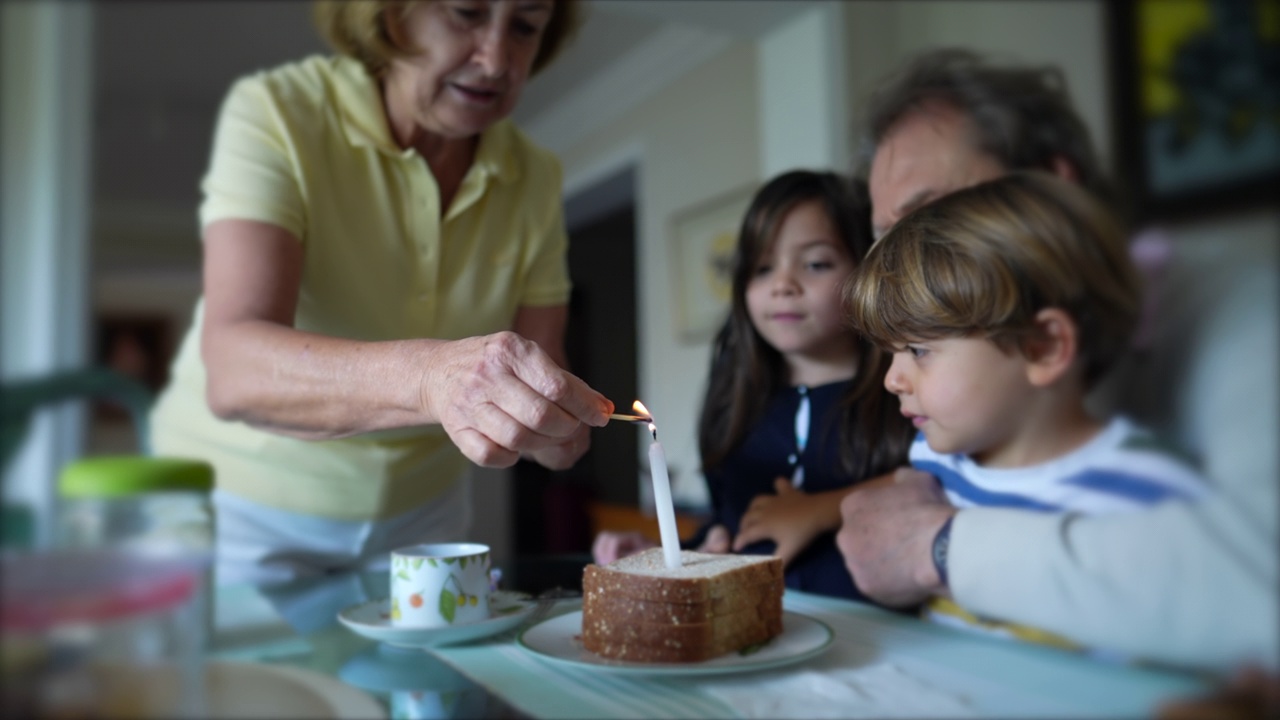 爷爷和孙子们一起庆祝生日。老爷爷在烛光纪念日前拥抱孩子们视频素材