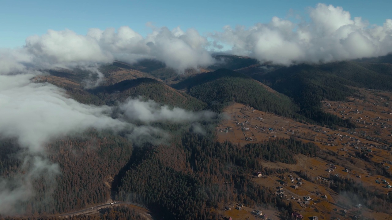 云雾密布的天，山上云杉林环绕的山村房屋的鸟瞰图。山区多云天气。秋天的森林里，薄雾吹过松树林视频素材