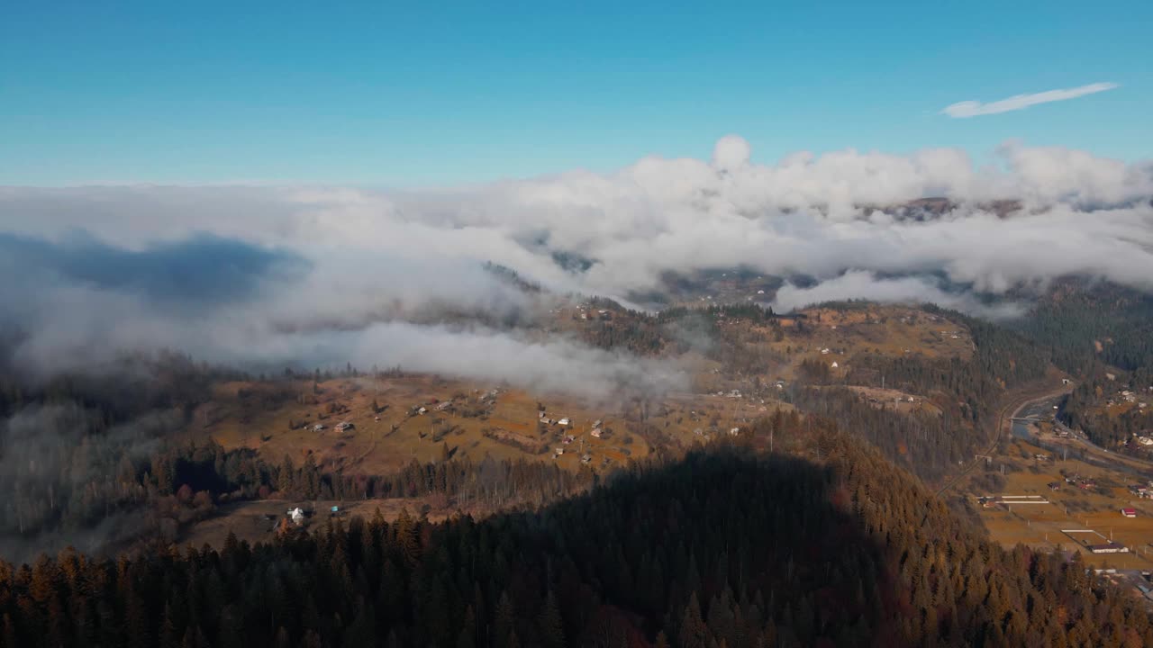 云雾密布的天，山上云杉林环绕的山村房屋的鸟瞰图。山区多云天气。秋天的森林里，薄雾吹过松树林视频素材