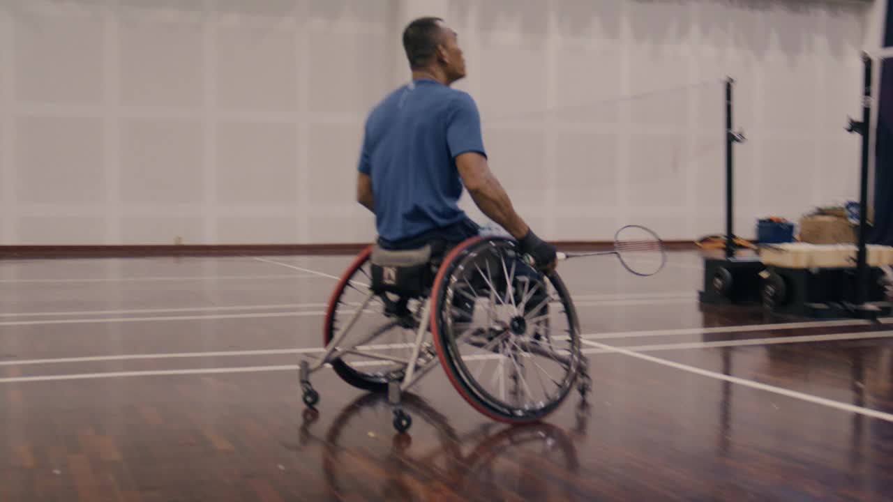 亚洲残疾羽毛球运动员坐在轮椅上与朋友们打羽毛球。视频下载