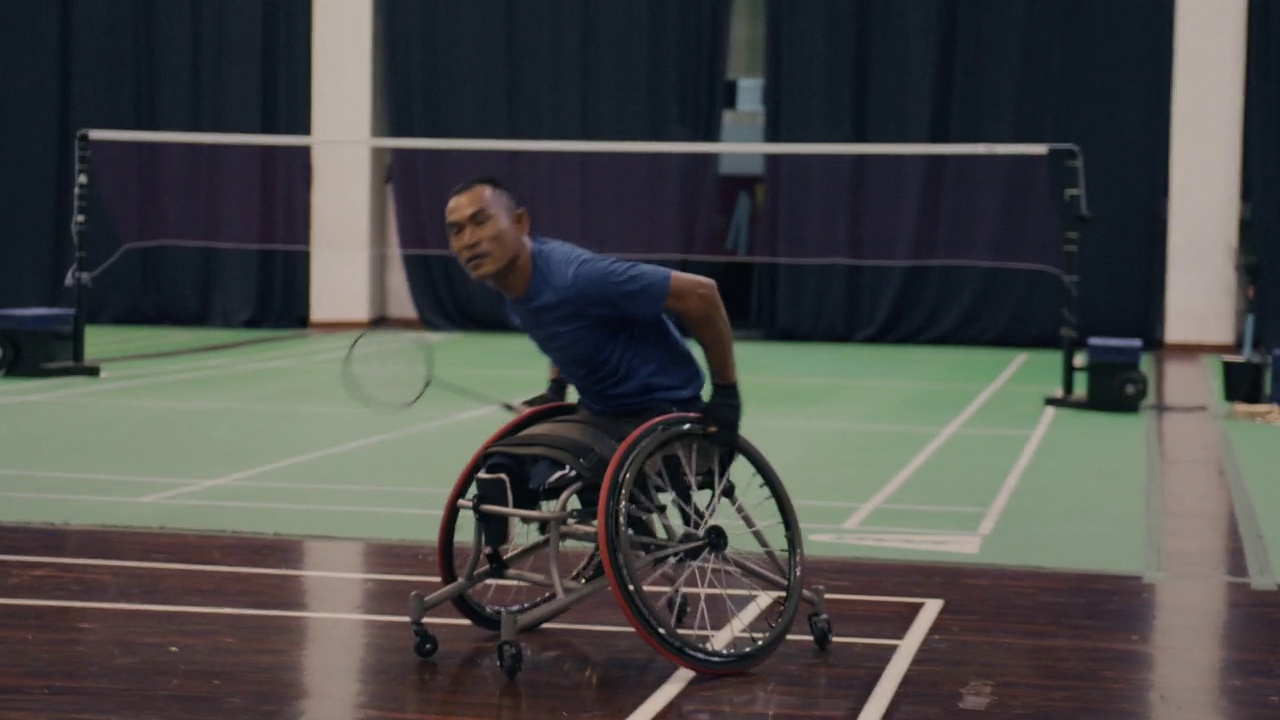 亚洲残疾羽毛球运动员坐在轮椅上与朋友们打羽毛球。视频下载