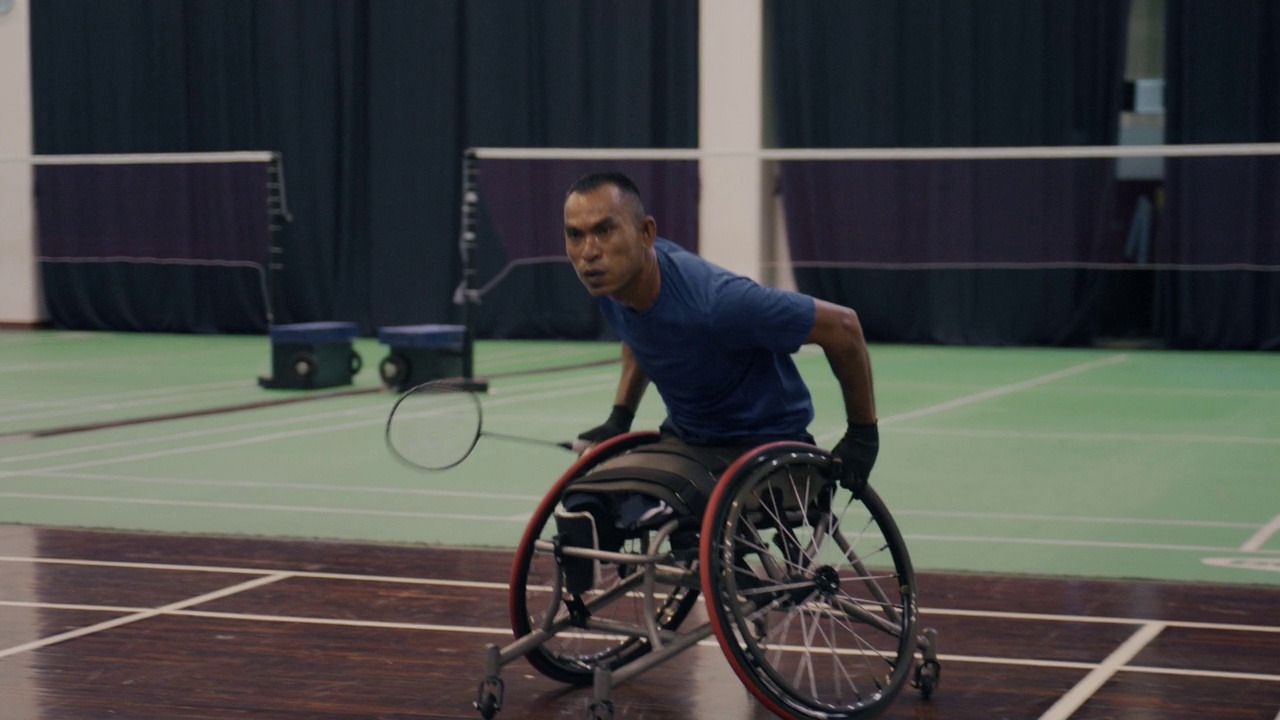 亚裔残疾男子穿着蓝色运动服坐在竞技轮椅上热身。视频下载