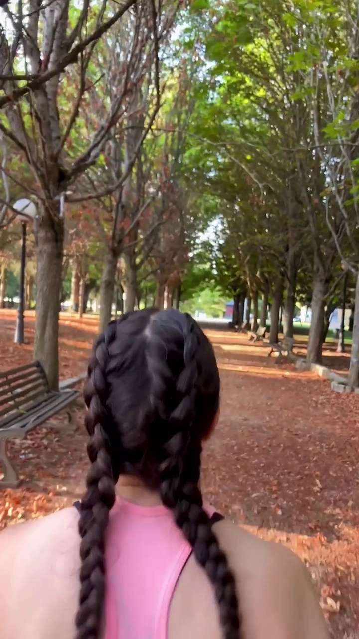 一个有魅力的运动女性在公园里向前奔跑的慢镜头垂直视频。视频素材