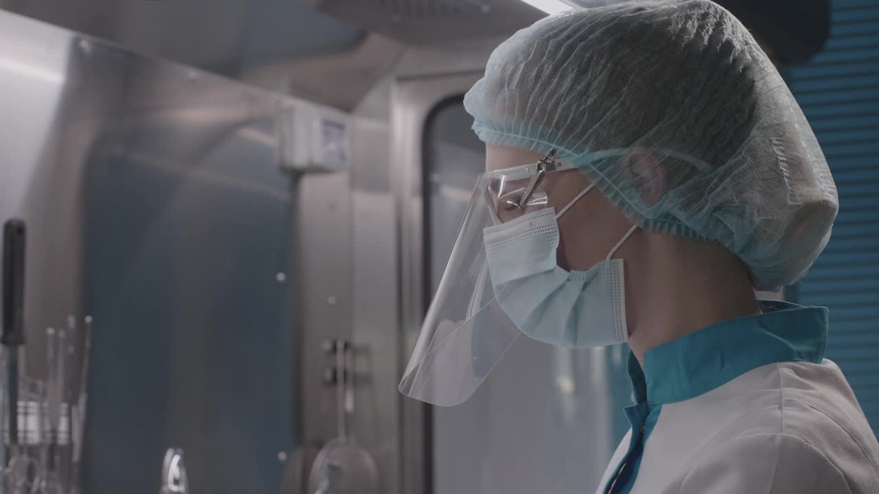 穿着防护服和口罩的女医务人员准备手术、移植或植入，无菌环境下研究生物样本，慢镜头视频下载