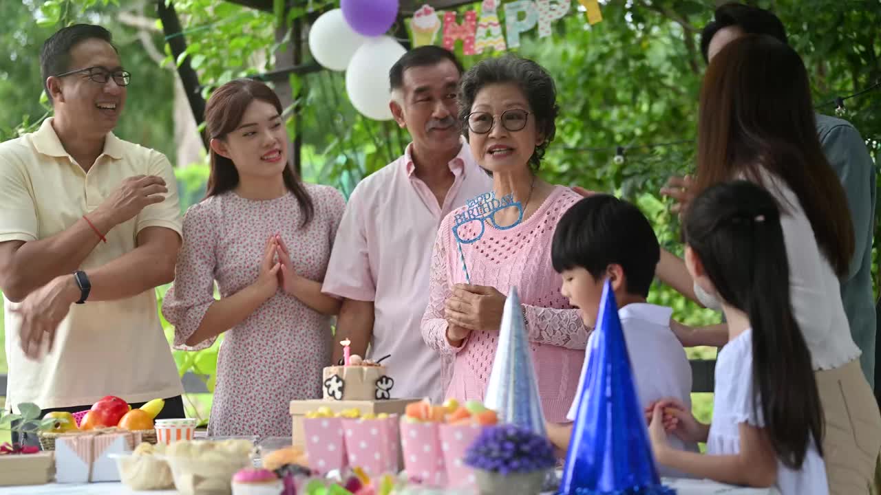 一位亚裔华人妇女在家人的簇拥下庆祝63岁生日。视频素材