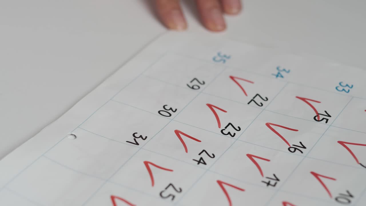 特写女性的手在日历上画红色的标记数字。年中的日期概念视频素材