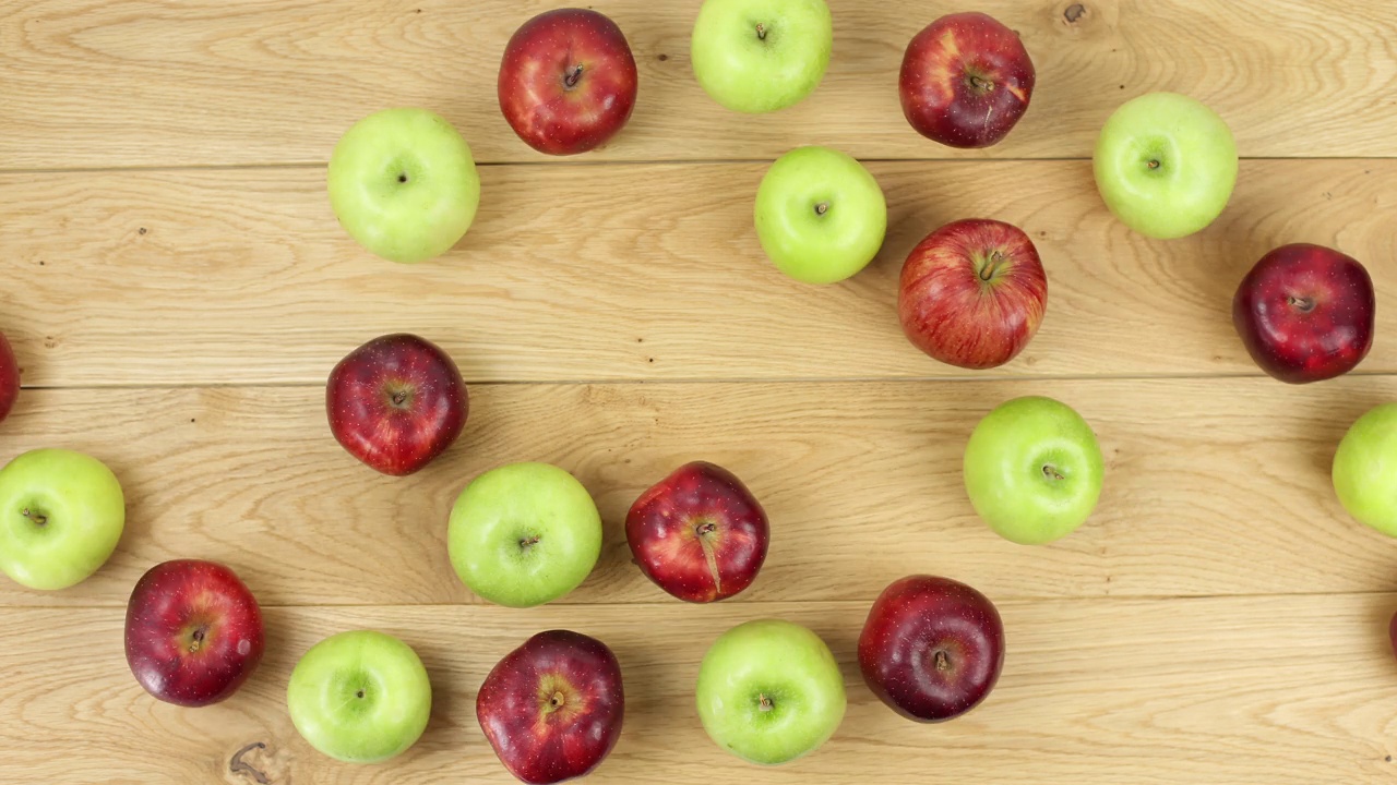 红苹果和青苹果的定格动作。平层。健康的食物和多汁的水果概念，在桌子上旋转视频下载