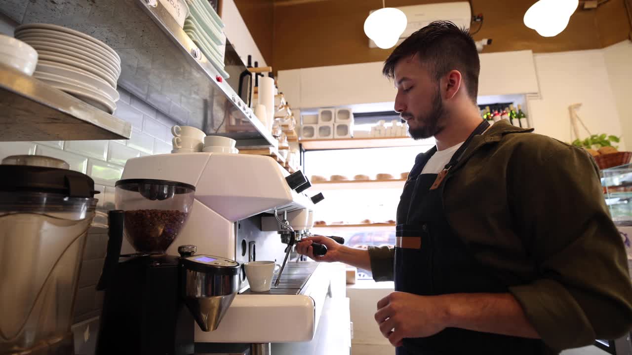 年轻的男咖啡师在咖啡店准备浓咖啡视频下载