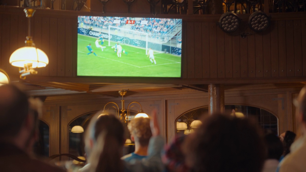 一群朋友在体育酒吧看电视直播的足球比赛。兴奋的球迷欢呼和喊叫。当球队进球并赢得足球世界杯时，年轻人庆祝。视频下载
