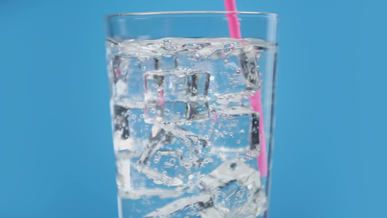 有人用粉红色的吸管混合凉水饮料。杯子里装满了气泡和冰块视频素材