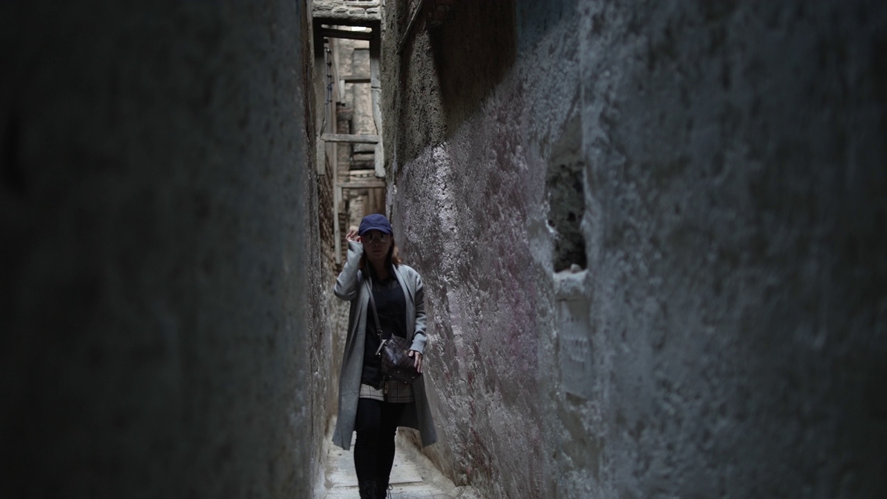 一名亚洲中国女游客走进摩洛哥非斯老麦地那的狭窄巷子视频下载