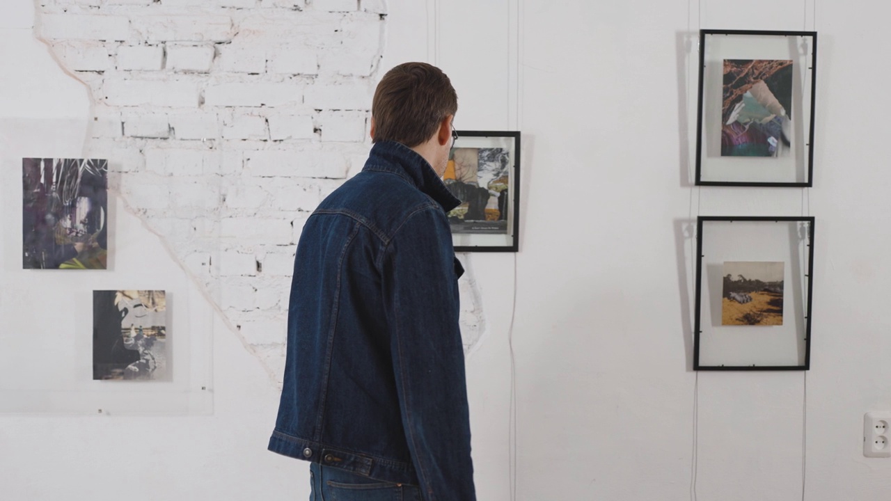 一名男子正在观看当代艺术拼贴画展览。视频下载