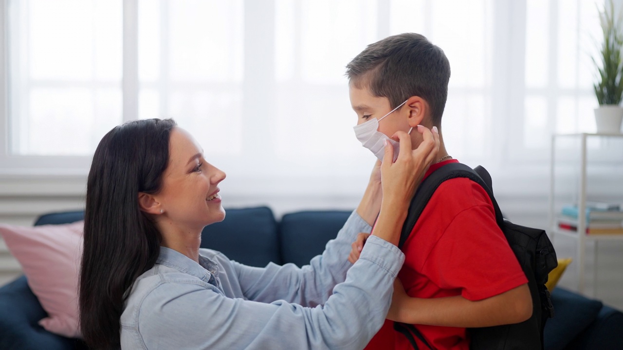 上学前，母亲帮儿子戴上口罩，预防疫情视频下载