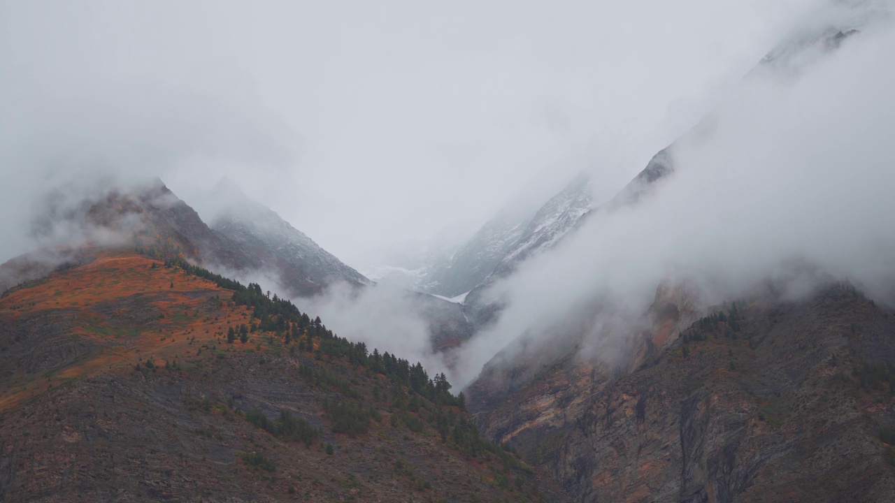 在印度喜马偕尔邦拉胡尔斯皮提的冬季，云团在雪覆盖的蒂南山谷的山峰下滚动的4K镜头。冬天雪山下的云。视频素材