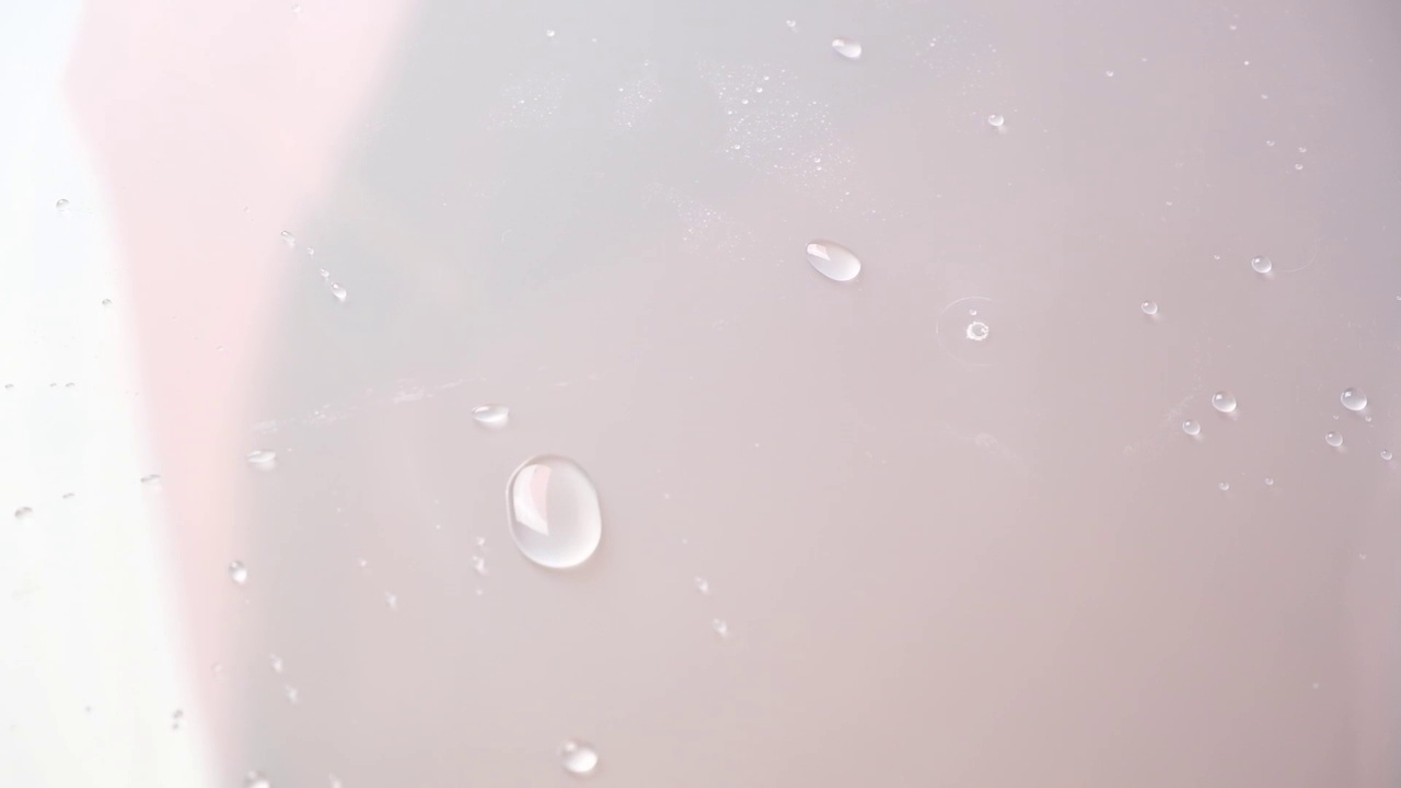 水滴在表面滑动。雨滴在玻璃上移动。玻璃上的水滴流动。视频素材