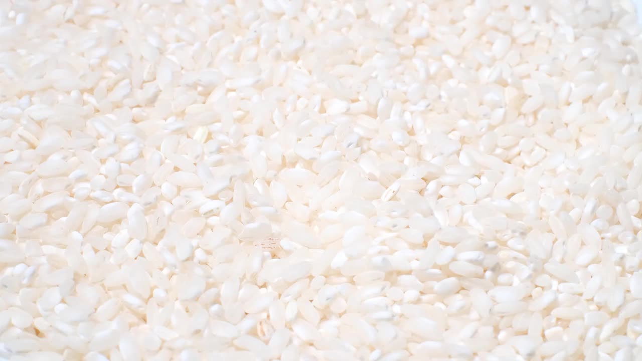 视频背景是白色背景上旋转的白色盘子上的干生白米。视频下载